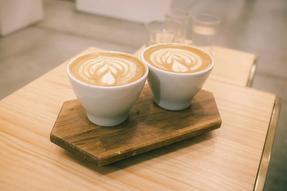 Dos tazas de café con leche sobre una tabla de madera.